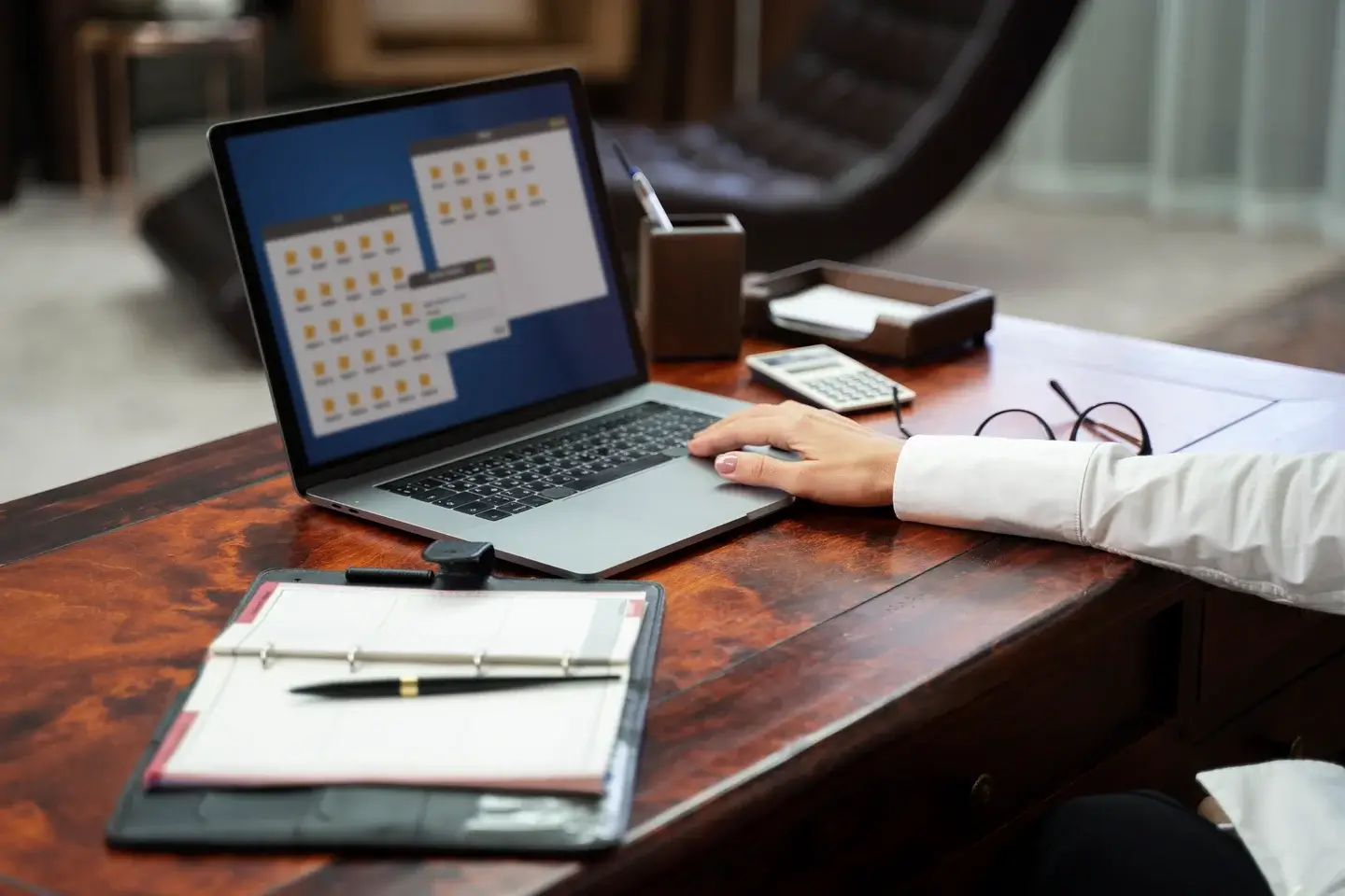 Osoba przy biurku sprawdza dokumenty na laptopie.
